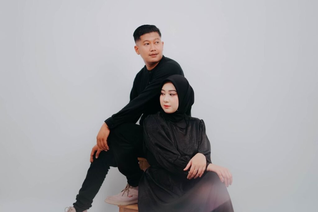 Home Stylish couple in black attire posing elegantly in a studio with a white background.