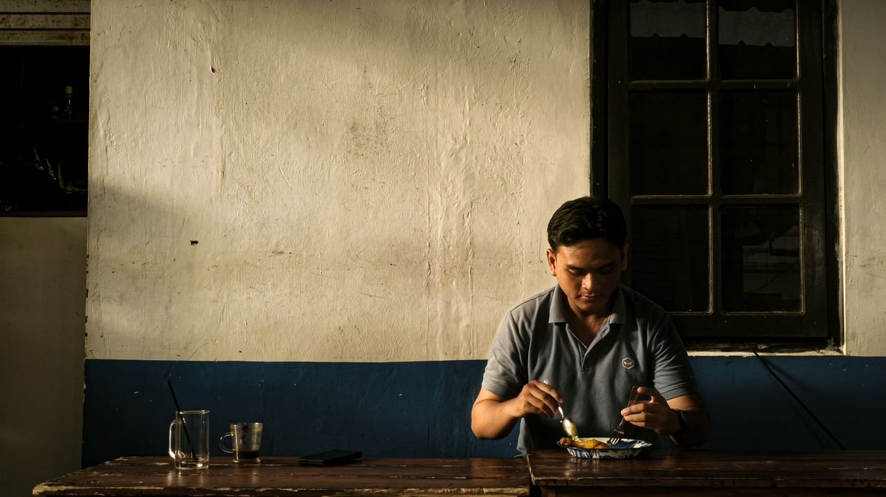 Home A man having a quiet meal in a rustic cafe with warm lighting and a rustic ambiance.